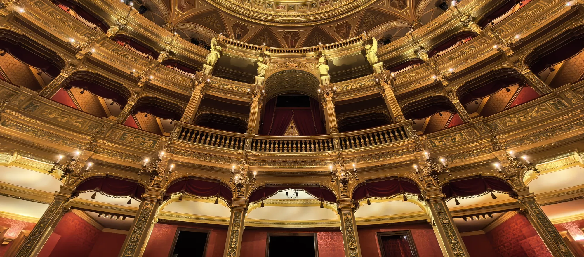 Filas de palcos dorados con revestimiento de terciopelo rojo que se curvan alrededor de la sala de la Ópera Estatal Húngara